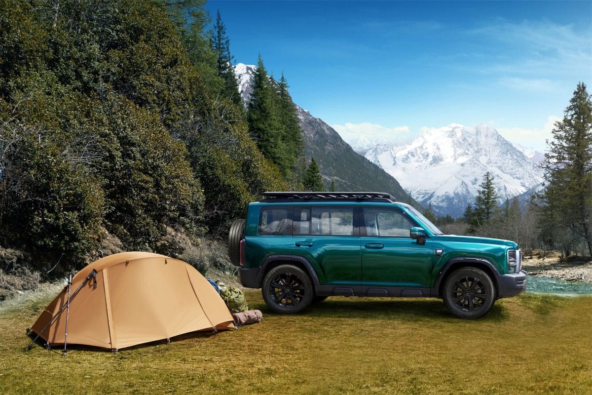 Green Haval V7 SUV parked beside a camping tent with mountain scenery, highlighting outdoor adventure lifestyle.